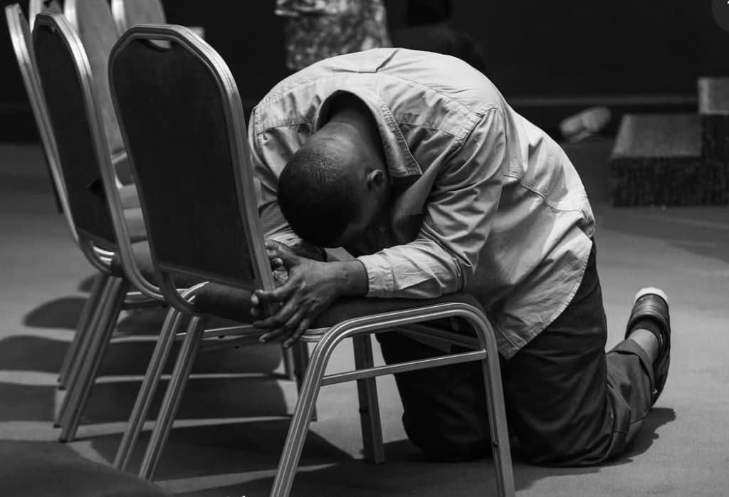 A man kneeling in prayer during a gathering